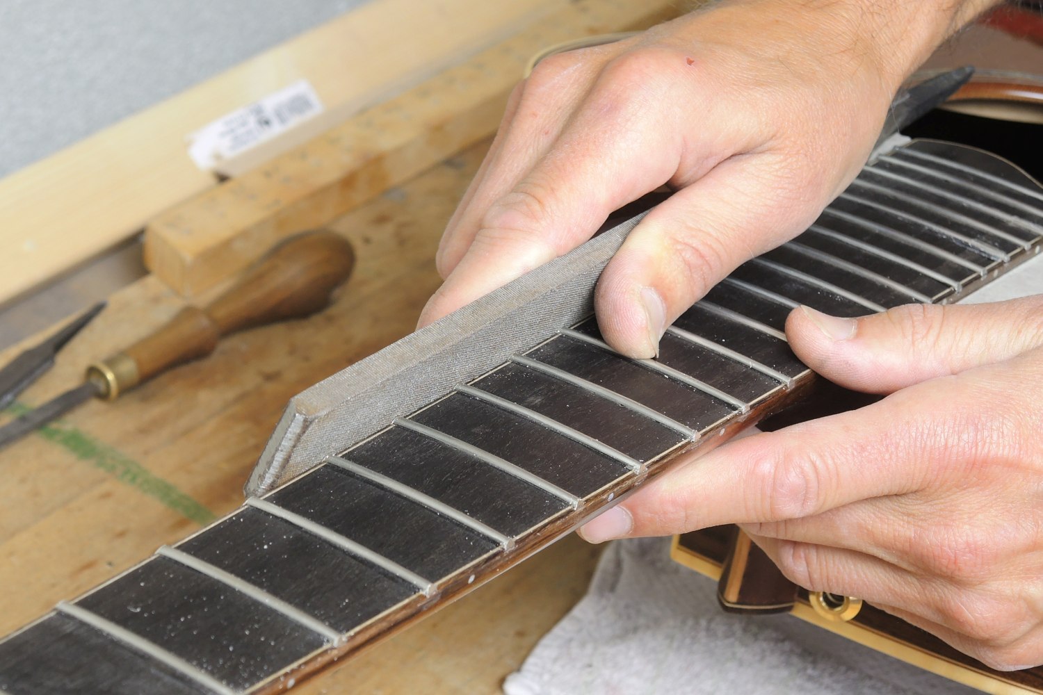 Re-fretting of an acoustic guitar - The frets are filed level with the fingerboard