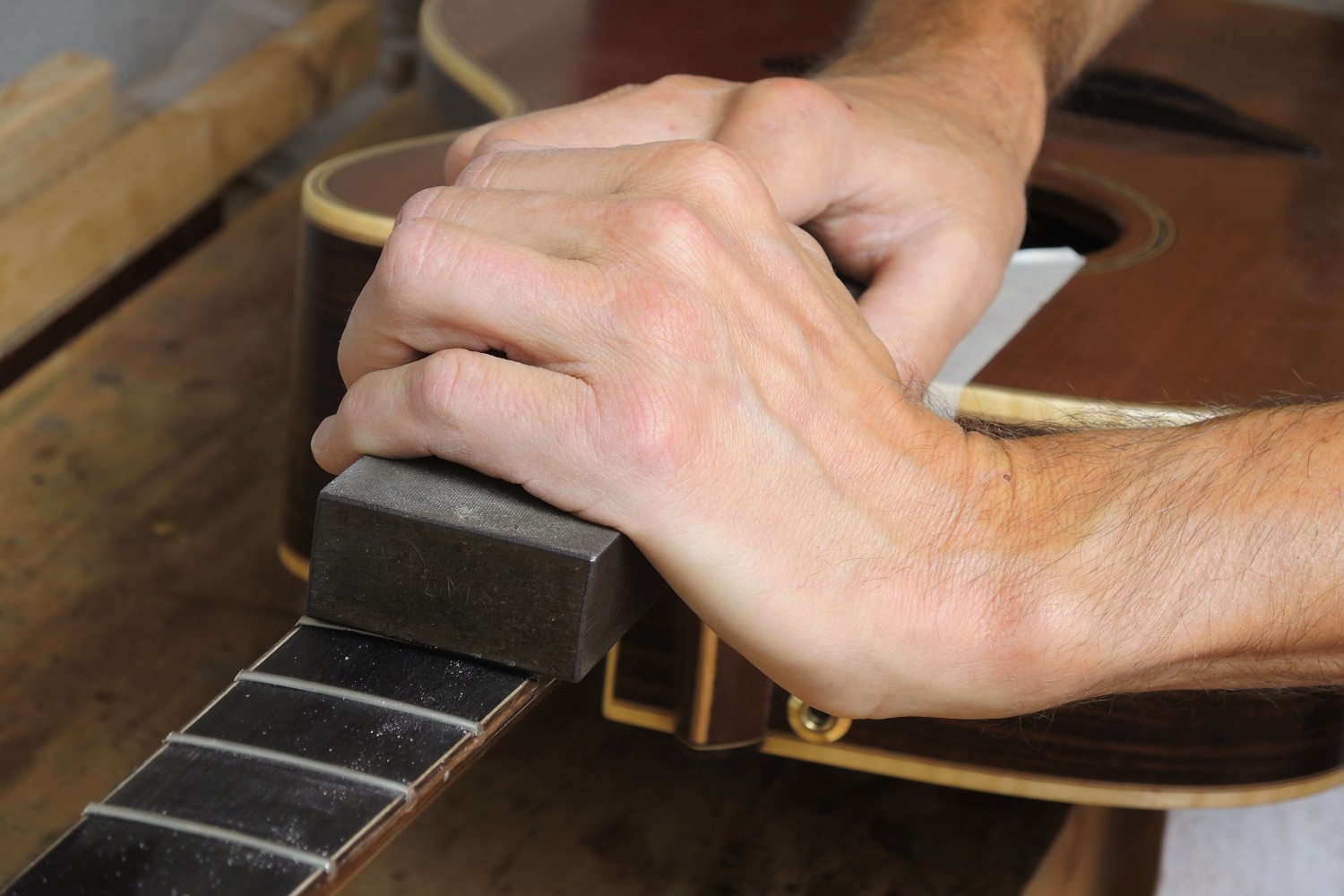 Re-fretting of an acoustic guitar - The frets are dressed with a block file (aligned to a uniform height)